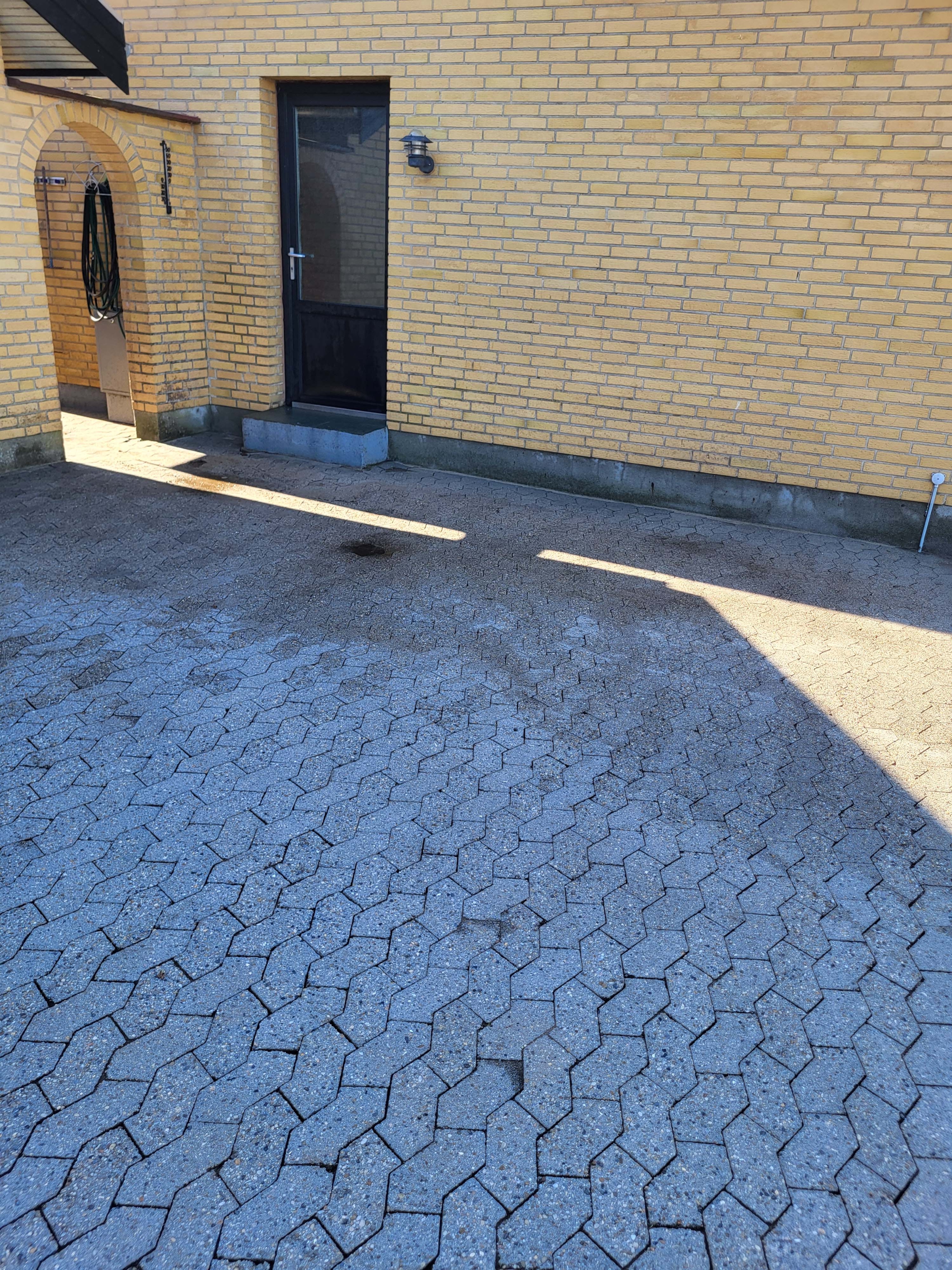 fliserensning ved gult hus
